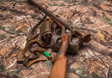 kamuflaj arka plan üzerinde double-barreled antika tüfek, bıçak ve mühimmat kemer