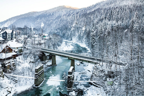 ледяная горная река, зимний лес на холмах, мост через реку
