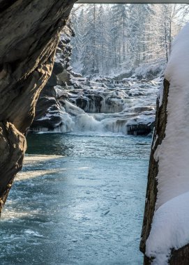 Buharlama taşlar, turuncu güneş ışığı, donmuş gölet arasında buzlu kış şelale
