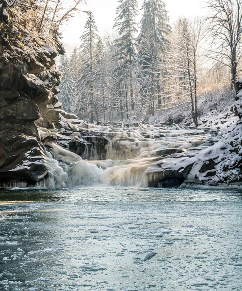 Buharlama taşlar, turuncu güneş ışığı, donmuş gölet arasında buzlu kış şelale