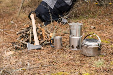 yakınındaki bir çeşidinde, mutfak eşyaları ve sırt çantası ve arka plan üzerinde kamp kamp woodstove axe