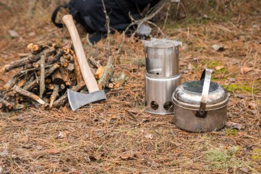 yakınındaki bir çeşidinde, mutfak eşyaları ve sırt çantası ve arka plan üzerinde kamp kamp woodstove axe