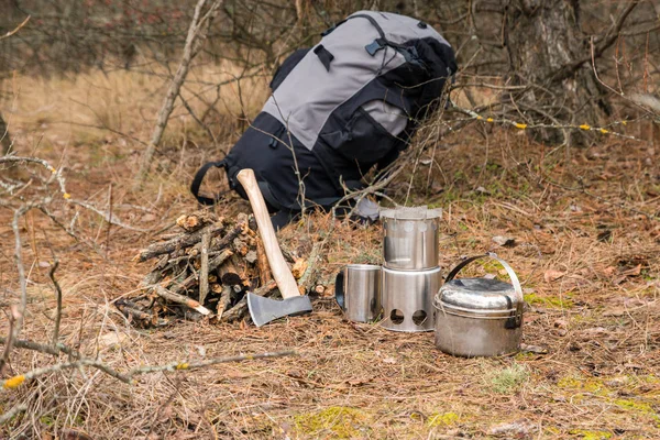 axe near a firewoods, camping woodstove, camping utensils and backpack on the background