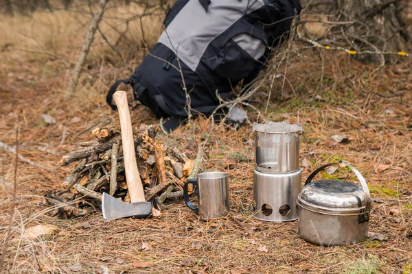 axe near a firewoods, camping woodstove, camping utensils and backpack on the background