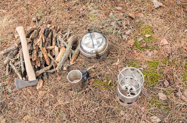 axe near a firewoods, camping woodstove, camping utensils and backpack on the background