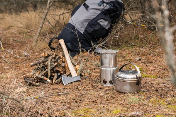 axe near a firewoods, camping woodstove, camping utensils and backpack on the background