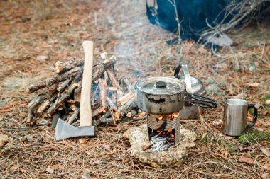 DIY woodstove, mutfak eşyaları ve sırt çantası ve arka plan üzerinde kamp kamp bir çeşidinde yakınındaki axe