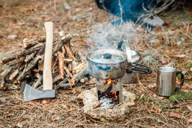 DIY woodstove, mutfak eşyaları ve sırt çantası ve arka plan üzerinde kamp kamp bir çeşidinde yakınındaki axe