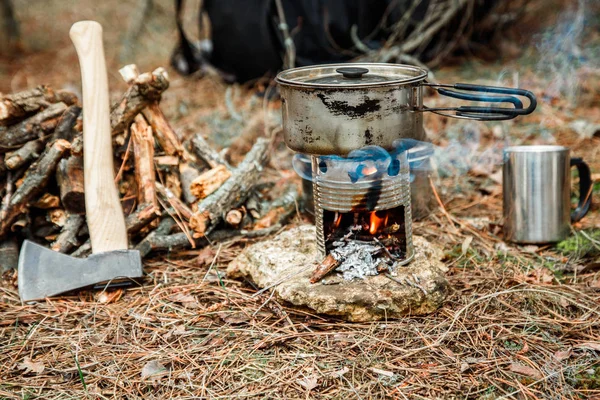 axe near a firewoods, camping diy woodstove, camping utensils and backpack on the background