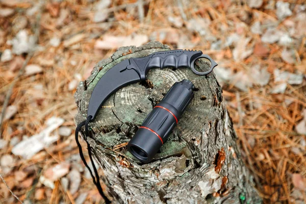 Монокль и карамбитный нож на пне в осеннем лесу — стоковое фото