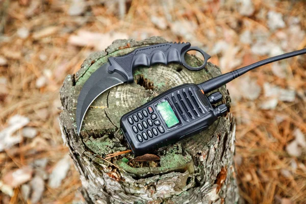 karambit knife and radio set on the stump in autumn forest