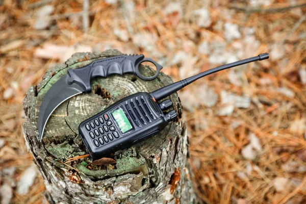 karambit knife and radio set on the stump in autumn forest