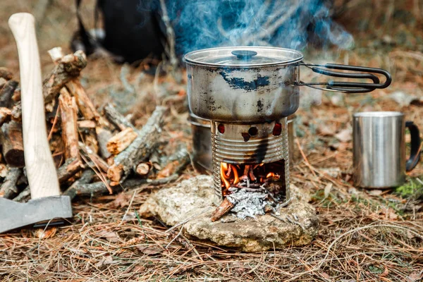 axe near a firewoods, camping diy woodstove, camping utensils and backpack on the background