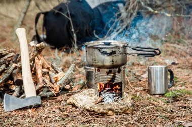 DIY woodstove, mutfak eşyaları ve sırt çantası ve arka plan üzerinde kamp kamp bir çeşidinde yakınındaki axe
