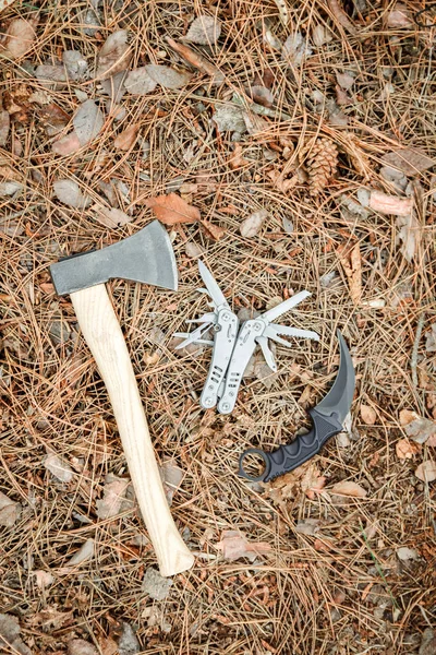 Топоры и туристические ножи, как карамбиты на земле, покрытые сосновыми иглами — стоковое фото
