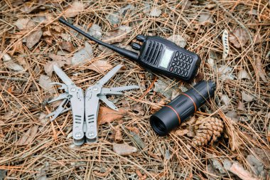 monokl, radyo seti ve multitool bıçağı yere çam iğneleri ile kaplı