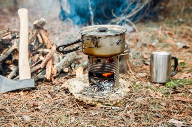 DIY woodstove, mutfak eşyaları ve sırt çantası ve arka plan üzerinde kamp kamp bir çeşidinde yakınındaki axe