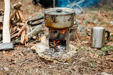 DIY woodstove, mutfak eşyaları ve sırt çantası ve arka plan üzerinde kamp kamp bir çeşidinde yakınındaki axe