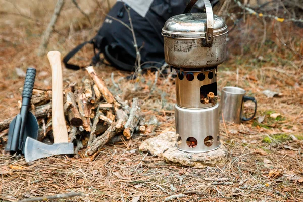 野营木炉和餐具, 斧头和铲子附近的火具, 背包的背景 — 图库照片