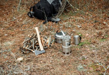 yakınındaki bir çeşidinde, mutfak eşyaları ve sırt çantası ve arka plan üzerinde kamp kamp woodstove axe