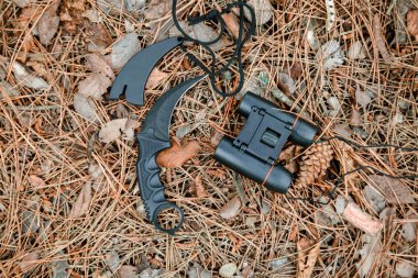 dürbün ve karambit bıçağı yere çam iğneleri ile kaplı