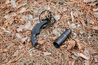 Tek gözlük ve karambit bıçağı yere çam iğneleri ile kaplı