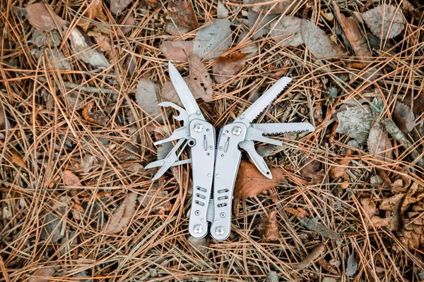 multi tool knife on the ground covered with pine needles