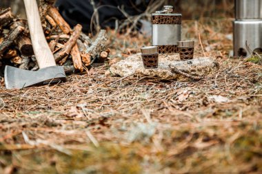 gözlük ile Flask, woodocak ve mutfak eşyaları kamp, bir firewoods yakın balta ve kazmacı kürek, arka plan üzerinde sırt çantası