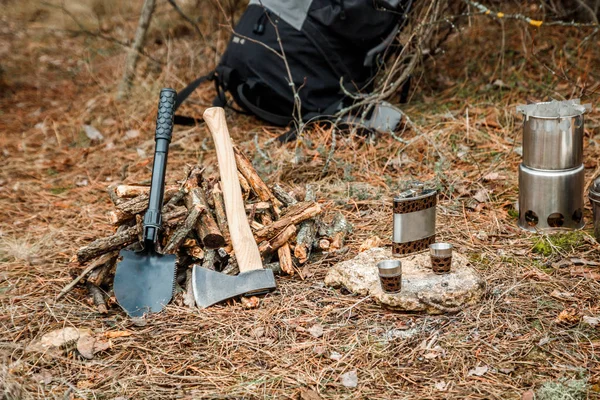 gözlük ile Flask, woodocak ve mutfak eşyaları kamp, bir firewoods yakın balta ve kazmacı kürek, arka plan üzerinde sırt çantası