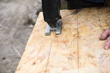 bir Jigsaw ile bir OSB paneli kesme, panelde el