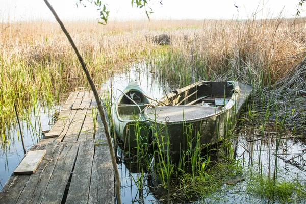 Vieux bateaux près d'une couchette en bois de planche sur le lac dans les roseaux — Photo