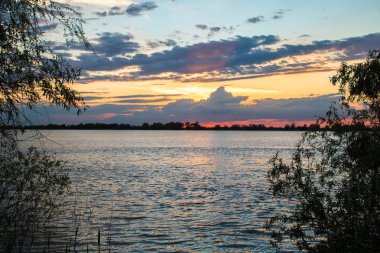 nehir tuna üzerinde güzel bulutlar ve turuncu gökyüzü ile doğal mavi ve kırmızı gün batımı