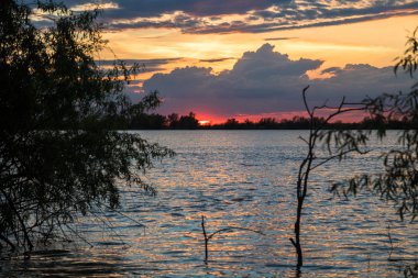 nehir tuna üzerinde güzel bulutlar ve turuncu gökyüzü ile doğal mavi ve kırmızı gün batımı