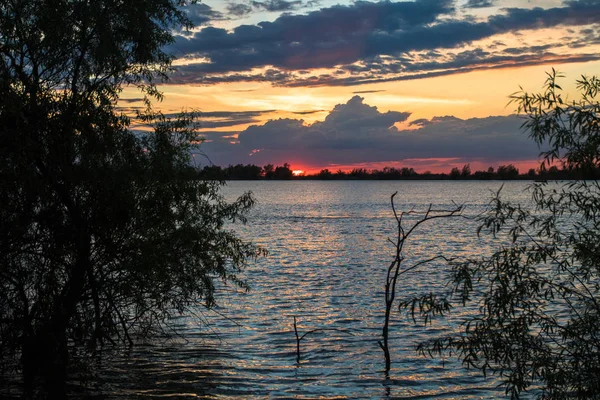 nehir tuna üzerinde güzel bulutlar ve turuncu gökyüzü ile doğal mavi ve kırmızı gün batımı