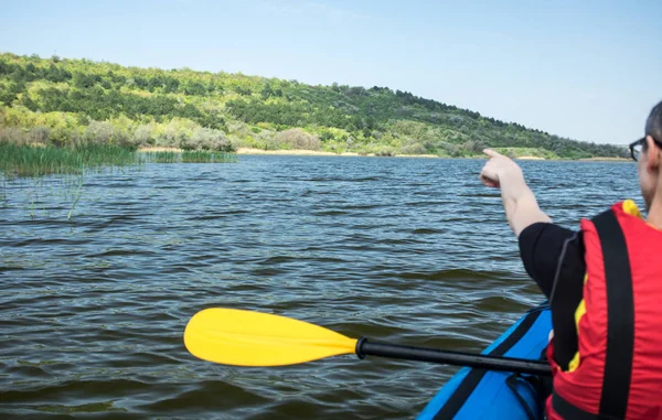 unrecognizable man in life vest kayaking on lake in a folding kayak