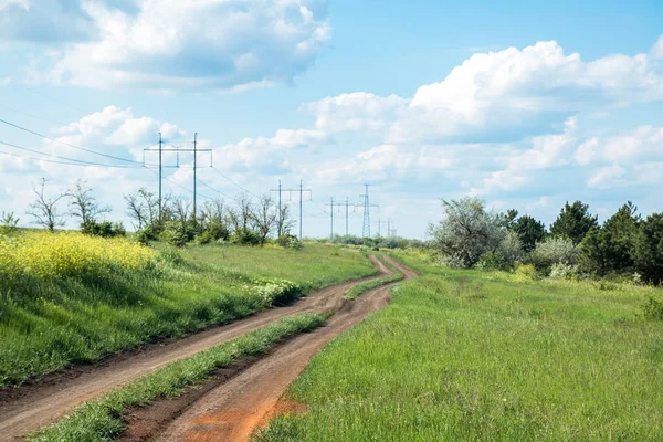 Route rurale entre champ et petite forêt, ciel bleu avec nuages — Photo