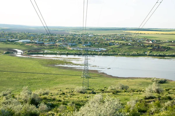湖と谷を横切る高圧電柱を持つ緑の谷の農村 — ストック写真