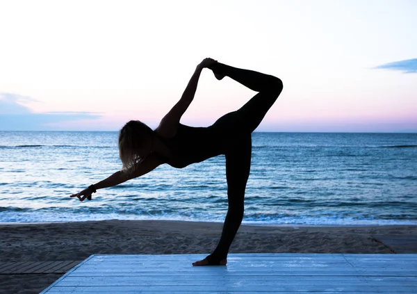 Женщина делает йогу на восходе солнца на море, силуэт йоги позы — стоковое фото