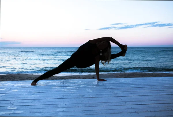 Nierozpoznawalna kobieta robi jogę na wschodzie słońca na morzu, sylwetka jogi stwarza — Zdjęcie stockowe
