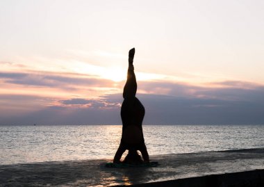 denizde gün doğumunda yoga headstand yapıyor güzel vücut ile tanınmaz kadın, yoga silueti pozlar