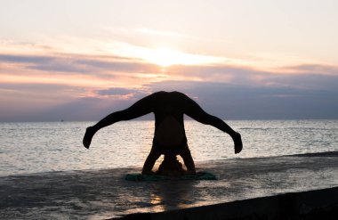 denizde gün doğumunda yoga headstand yapıyor güzel vücut ile tanınmaz kadın, yoga silueti pozlar