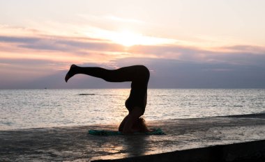 denizde gün doğumunda yoga headstand yapıyor güzel vücut ile tanınmaz kadın, yoga silueti pozlar