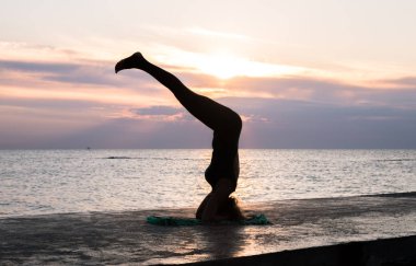 denizde gün doğumunda yoga headstand yapıyor güzel vücut ile tanınmaz kadın, yoga silueti pozlar