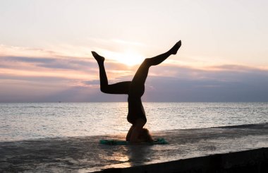 denizde gün doğumunda yoga headstand yapıyor güzel vücut ile tanınmaz kadın, yoga silueti pozlar