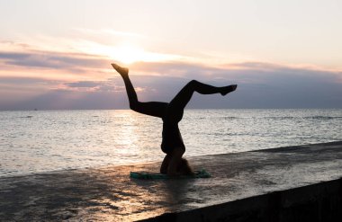 denizde gün doğumunda yoga headstand yapıyor güzel vücut ile tanınmaz kadın, yoga silueti pozlar