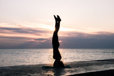 denizde gün doğumunda yoga headstand yapıyor güzel vücut ile tanınmaz kadın, yoga silueti pozlar