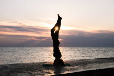 denizde gün doğumunda yoga headstand yapıyor güzel vücut ile tanınmaz kadın, yoga silueti pozlar