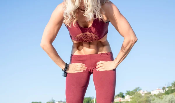 Caucasian healthy blonde woman with beautiful body doing uddiyana bandha yoga at sunrise on the beach, yoga poses — Stock Photo, Image