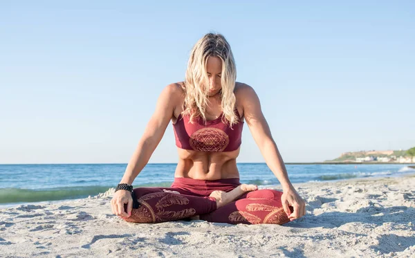 Kaukaski zdrowe blond kobieta z pięknym ciałem robi Uddiyana Bandha jogi na wschód słońca na plaży, Joga stwarza — Zdjęcie stockowe