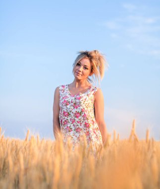 Günbatımında sarı buğday tarlasında giyinmiş genç, baştan çıkarıcı, kırsal sarı saçlı kadın.